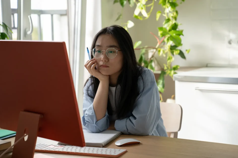 A young east asian student watching a video with translated subtitles